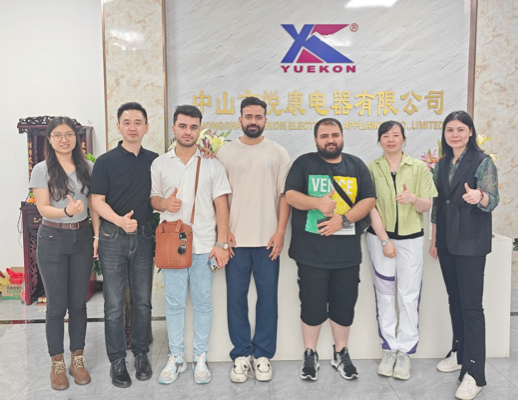Сотрудники Zhongshan Yuekon Electrical Appliances Co., Limited и международные клиенты позируют вместе, символизируя успешные и совместные деловые отношения.